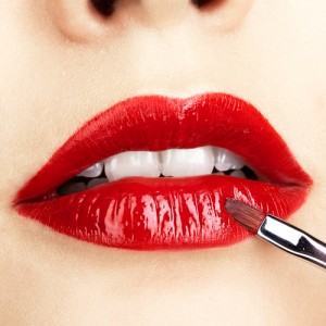 Wear Blue-Based Lipstick Woman applying red lipstick to her lips with a makeup brush