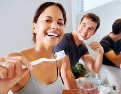 male and adult couple happily brushing their teeth in a bathroom