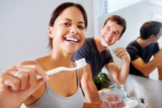 male and adult couple happily brushing their teeth in a bathroom