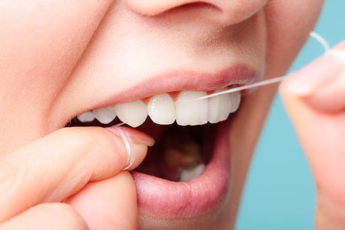 smiling women using dental floss white healthy teeth-img-blog