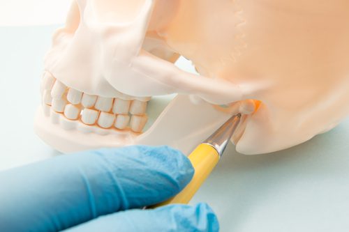 physician indicates on the mandibular joint or human ear bone canal as the source of the symptom