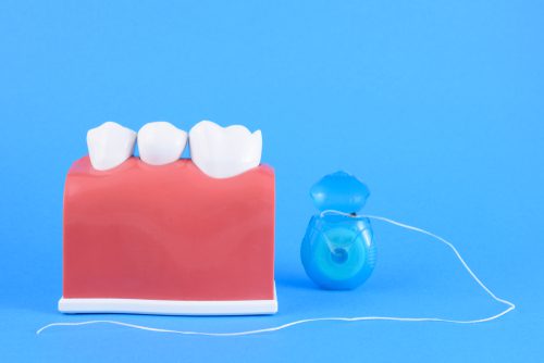 false mouth dentist in blue background with equipment for toothbrush and floss-img-blog