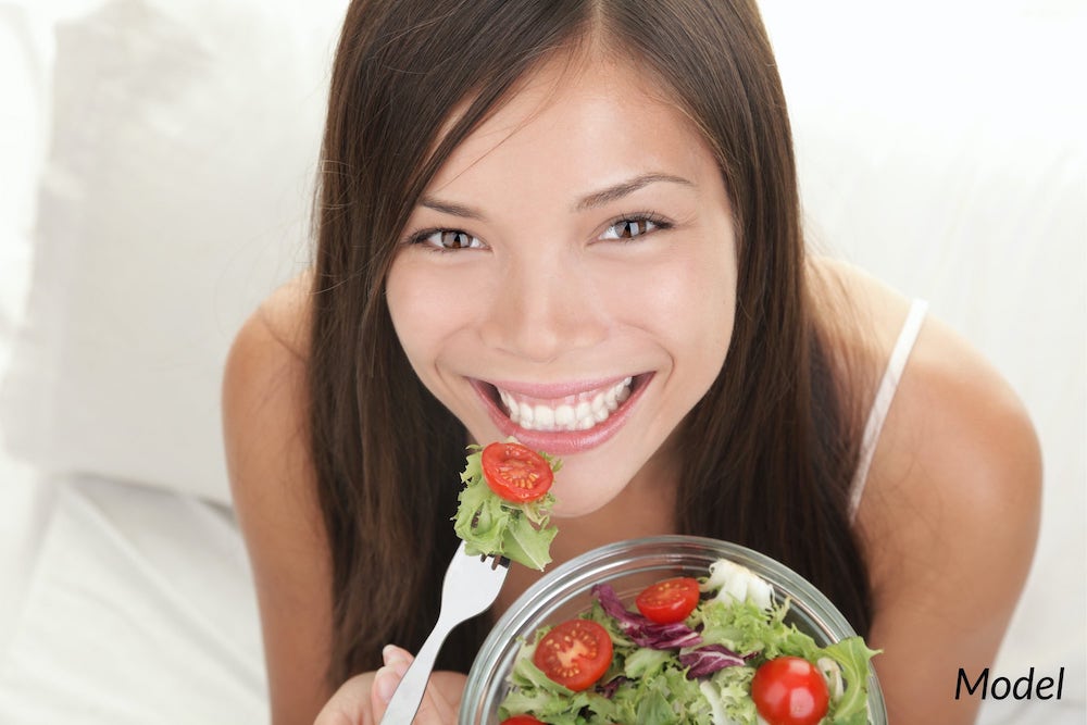 Young woman eating a salad to better the health of her teeth.