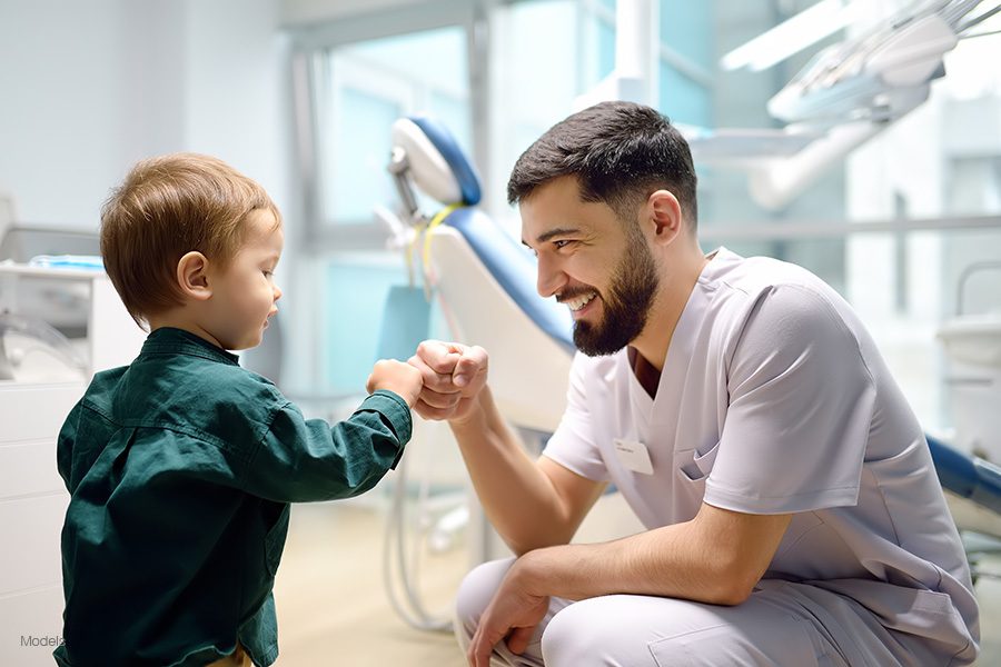 a smiling dentist fist-bumps with a happy toddler patient